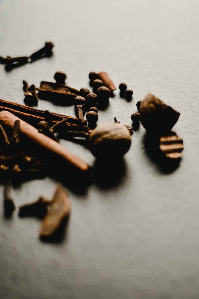 A moody still life photograph of assorted whole spices on a textured background.